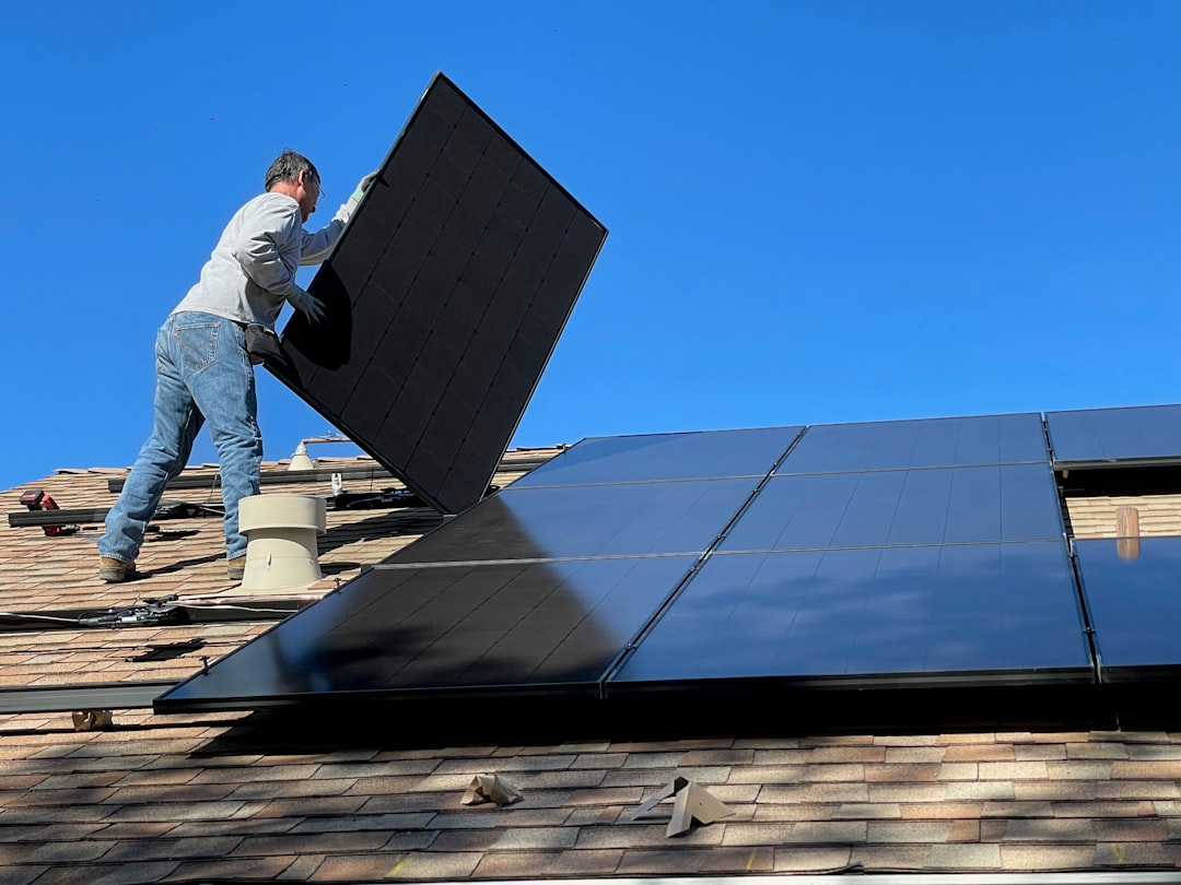 services-01 Worker installing solar panels on a roof